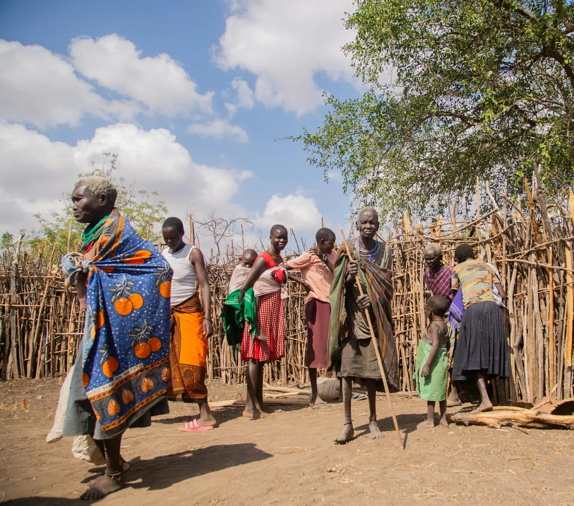 A vibrant scene depicting African villagers in traditional attire outdoors.